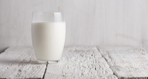 Glass of milk standing on old wooden table