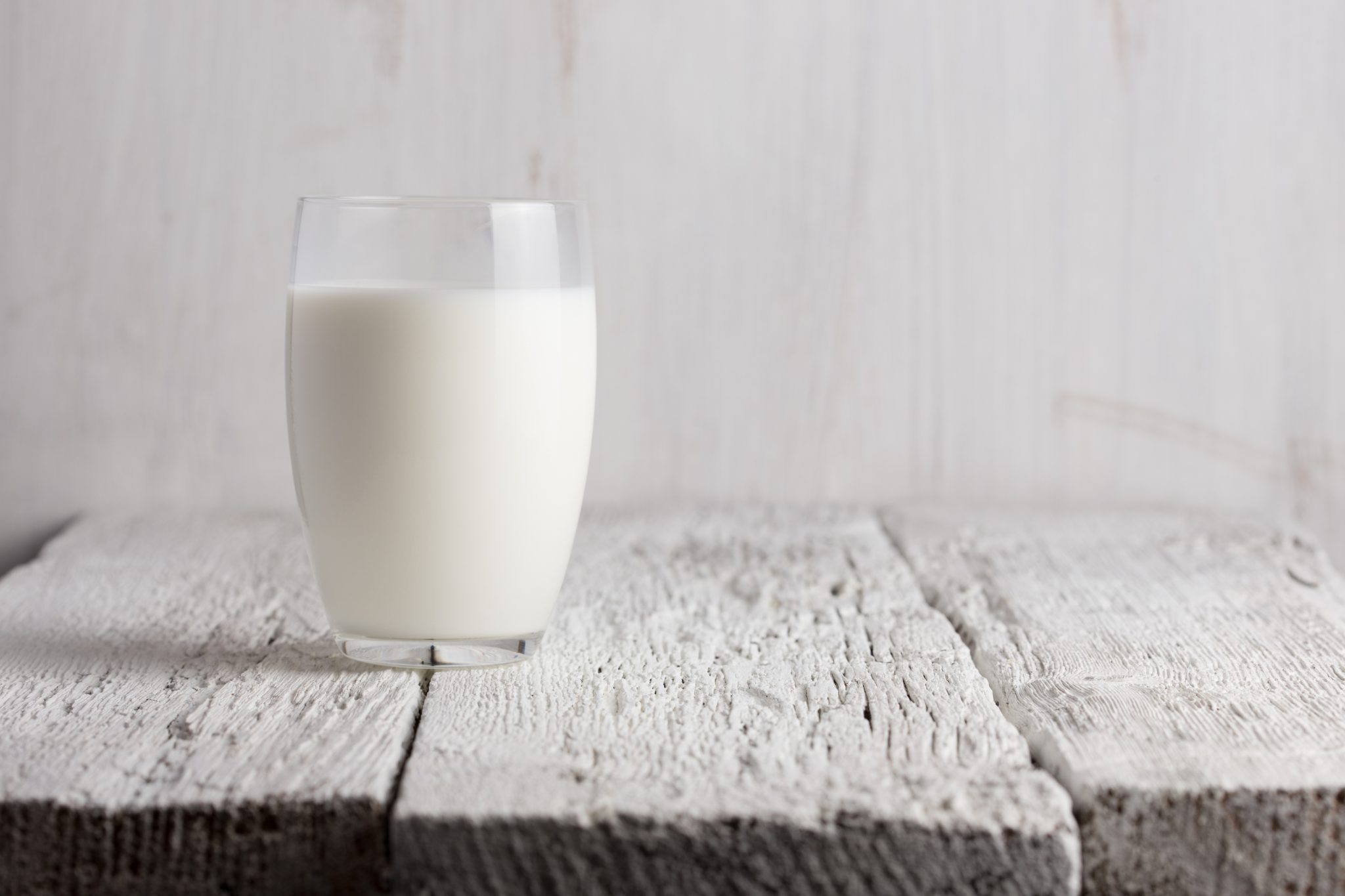 Glass of milk standing on old wooden table