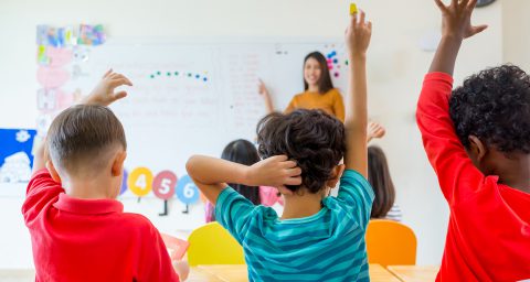 kids raising their arms up in a class room