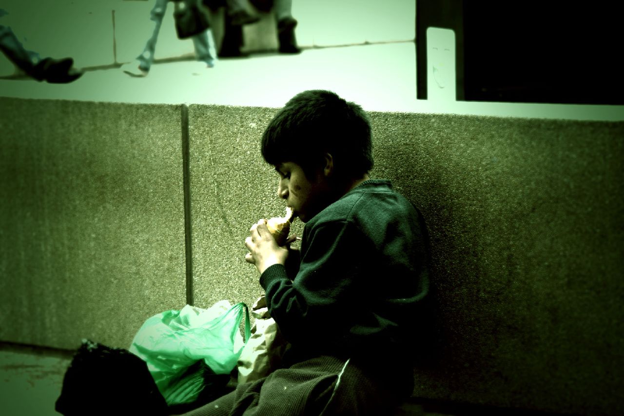 Homeless boy eating food on the street