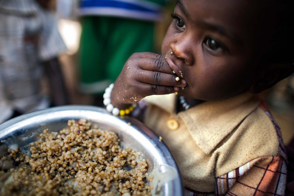 A child eats lentils in a food distribution center in the Rwanda camp