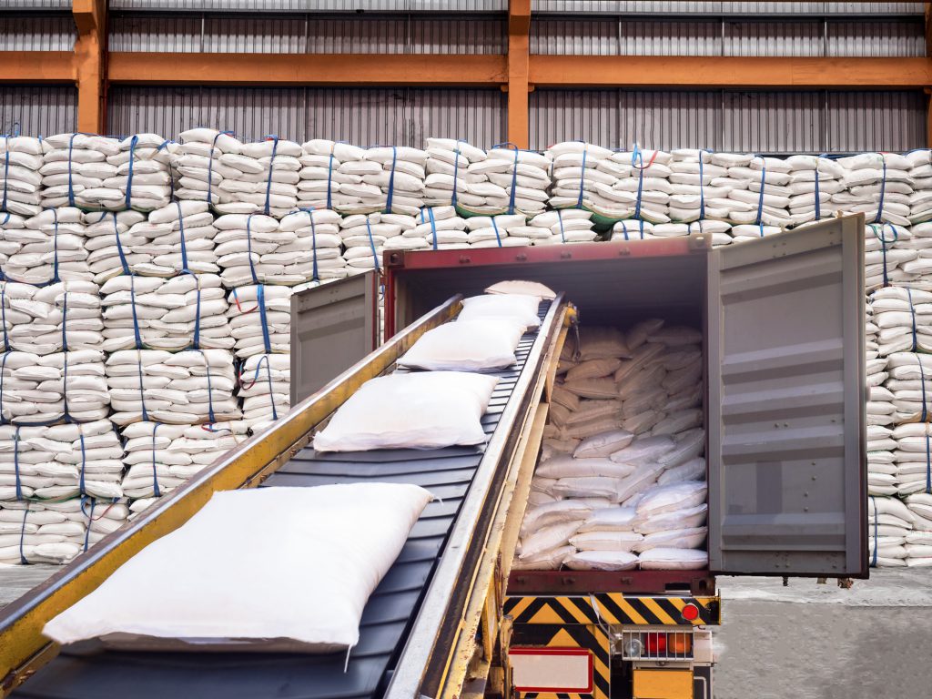 White bags of sugars from warehouse are staffing in container for export