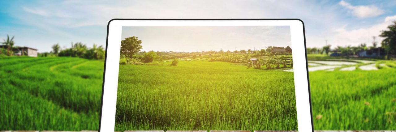 Tablet on wooden table with countryside in background