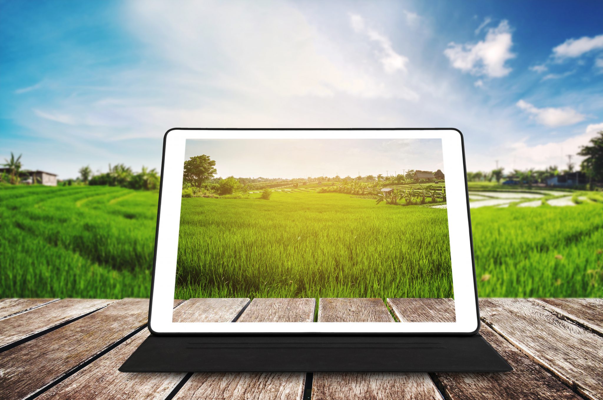 Tablet on wooden table with countryside in background